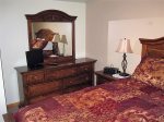 Just off the living room, the main bedroom has a pillow top queen bed and matching vanity dresser.